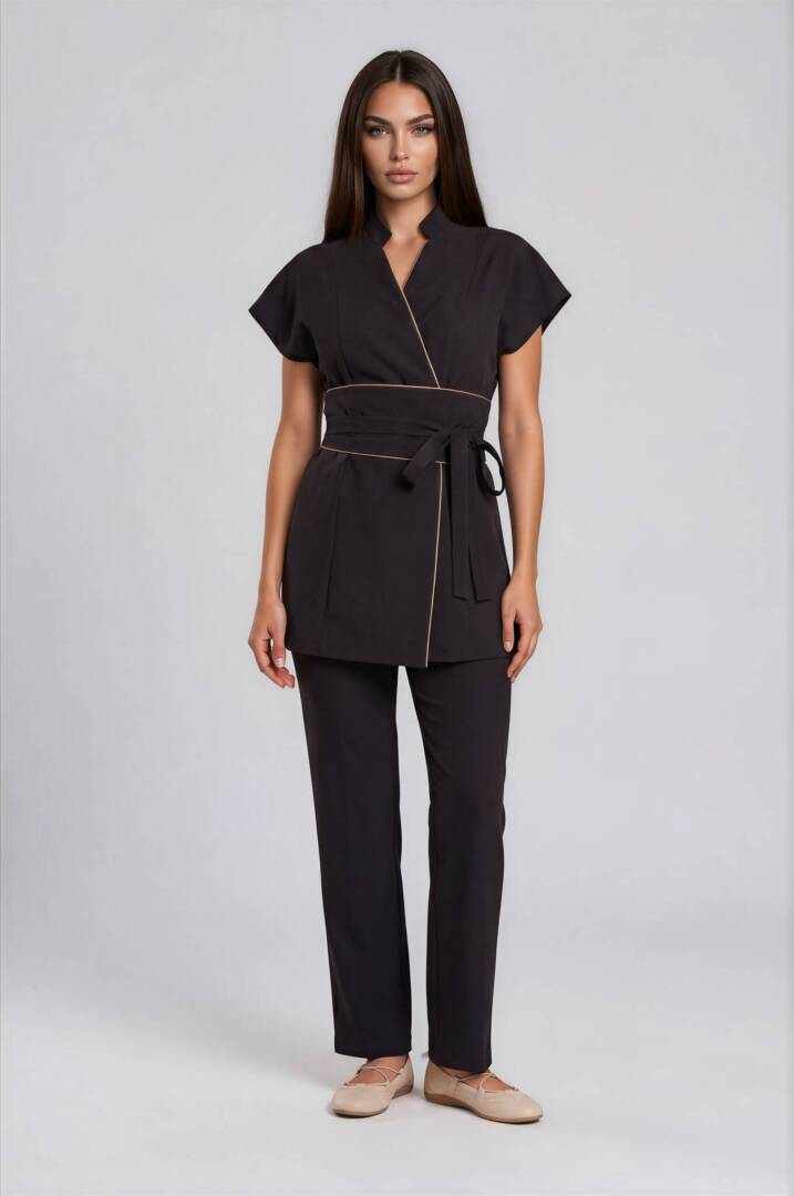 belted spa uniform Luxury black spa uniform featuring an elongated wrap tunic with elegant beige piping and a wide wrap belt.